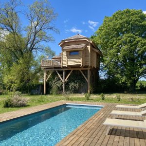 Cabane perchée en bois avec piscine, entourée de verdure à Midi-Pyrénées.