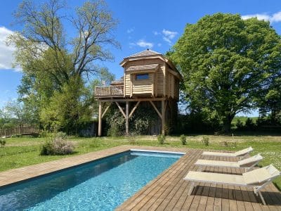 Cabane perchée en bois avec piscine, entourée de verdure à Midi-Pyrénées.