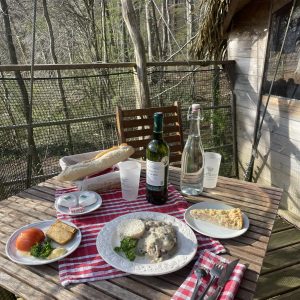 Repas savoureux sur la terrasse d'une cabane dans les arbres, entourée de verdure.