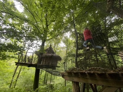 Cabane dans les arbres, perchée entre les feuillages, avec un filet suspendu pour l'aventure.