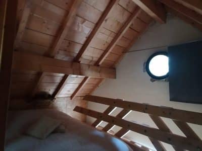 Chalet en bois avec lit douillet et fenêtre ronde, situé en Champagne-Ardenne.