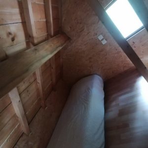 Cabane en bois à Champagne-Ardennes, avec un lit confortable sous un velux.
