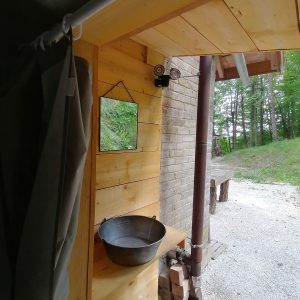 Hébergement insolite en bois avec un lavabo en métal et vue sur la nature.