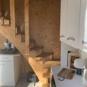 Escalier en bois menant à une mezzanine dans un hébergement insolite et moderne.