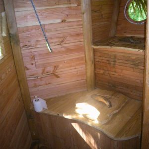 Cabane en bois avec un intérieur chaleureux, banc en bois et fenêtre ronde. Ambiance cocooning.