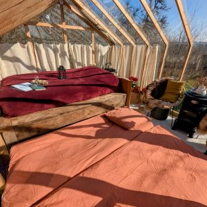 Hébergement insolite en serre avec lits douillets et vue panoramique sur la nature.