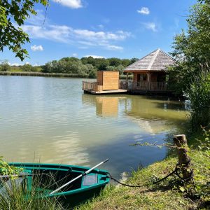 Cabane sur pilotis au bord dun lac, entourée de verdure et dun canoë.