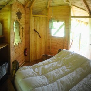 Cabane en bois avec intérieur chaleureux, lit douillet et décor en bois naturel.