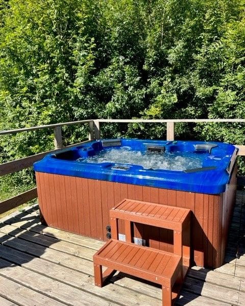 Chalet avec jacuzzi extérieur, entouré de verdure luxuriante et de tranquillité.