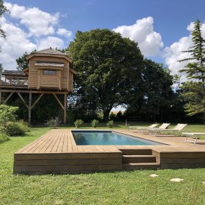 Cabane perchée en bois avec piscine, entourée de verdure à Midi-Pyrénées.