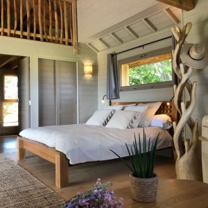 Chalet en bois lumineux avec lit douillet et décoration naturelle.