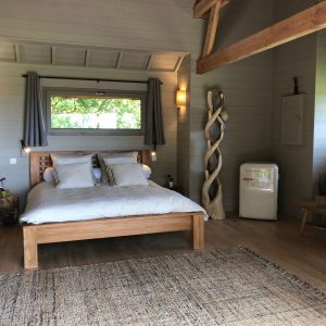 Chalet moderne en Midi-Pyrénées, avec lit en bois et décoration chaleureuse.