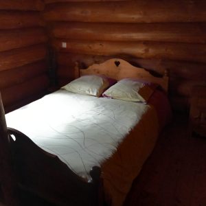 Chalet en bois chaleureux avec un lit douillet et une ambiance rustique apaisante.