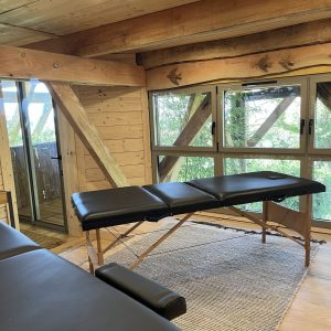 Cabane en bois avec vue, équipée dune table de massage et décor chaleureux.
