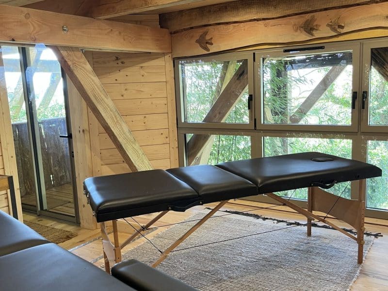 Cabane en bois avec vue sur la nature, équipée dune table de massage.