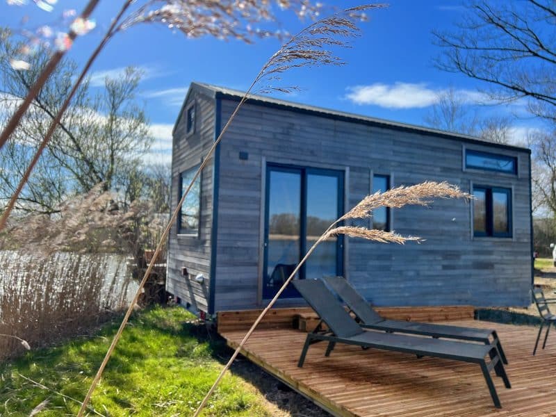 Cabane en bois au bord de leau, avec terrasse en bois et vue dégagée sur la nature.