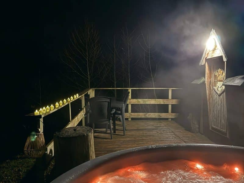 Chalet romantique avec jacuzzi, éclairé par des lumières douces dans la nuit.