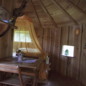 Cabane en bois en Auvergne, avec un lit à baldaquin et des décorations naturelles.