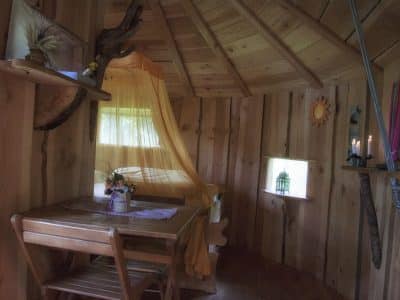 Cabane en bois en Auvergne, avec un lit à baldaquin et des décorations naturelles.