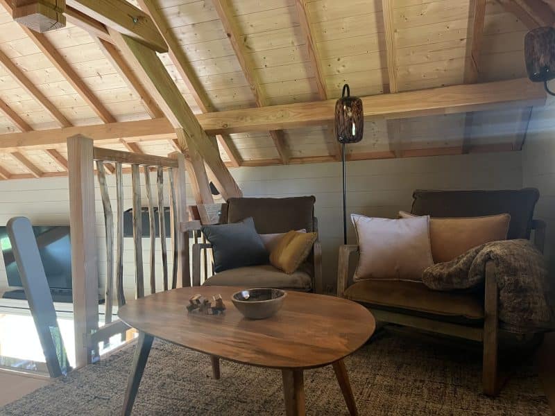 Chalet cosy avec poutres apparentes, coin salon chaleureux et décor moderne.