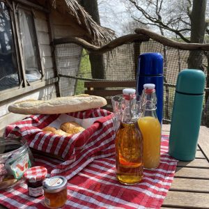 Un cabanon dans les arbres avec un petit déjeuner gourmand sur une table en bois.
