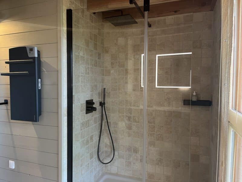 Salle de bain moderne dun chalet, avec douche à litalienne et éclairage LED.