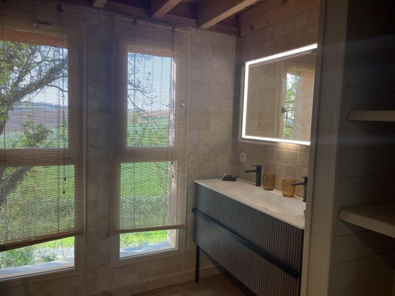 Salle de bain moderne dans un chalet, avec vue sur la nature et lumière naturelle.
