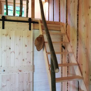 Escalier en bois naturel menant à une mezzanine dans une cabane en bois chaleureuse.