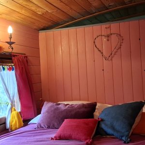 Chambre cocooning dans une cabane colorée, décorée de coussins et d'un cœur en guirlande.