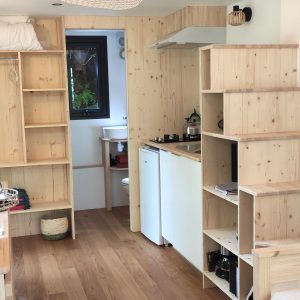 Un chalet en bois lumineux avec cuisine équipée et escaliers en bois, ambiance chaleureuse.