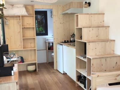 Un chalet en bois lumineux avec cuisine équipée et escaliers en bois, ambiance chaleureuse.