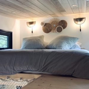 Chambre cocooning en hauteur, lit douillet avec éclairage doux et décor naturel.