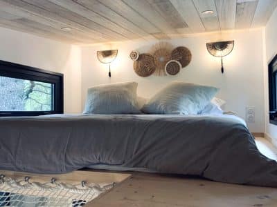 Chambre cocooning en hauteur, lit douillet avec éclairage doux et décor naturel.