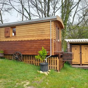 Charmante roulotte en bois surélevée, entourée de verdure, avec toilettes séparées en bois.