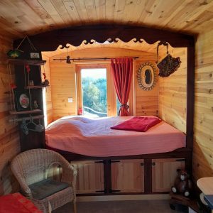 Chalet en bois chaleureux avec lit douillet, fenêtres lumineuses et décoration rustique.