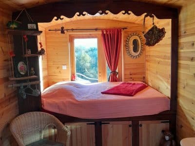 Chalet en bois chaleureux avec lit douillet, fenêtres lumineuses et décoration rustique.