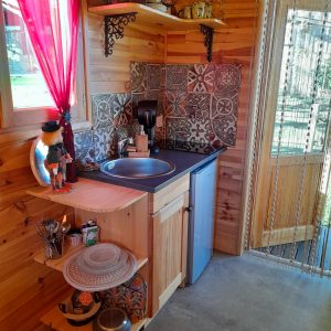 Intérieur d'un chalet en bois, avec un coin cuisine décoré de carreaux colorés et d'objets