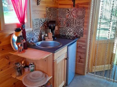 Intérieur d'un chalet en bois, avec un coin cuisine décoré de carreaux colorés et d'objets