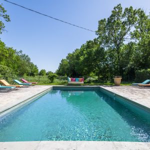 Une villa avec piscine, entourée de verdure, idéale pour des vacances relaxantes.