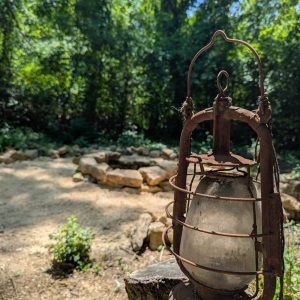 Une cabane rustique au cœur de la forêt, avec une vieille lanterne en métal en premier plan.