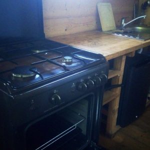 Cuisine rustique dans un chalet en bois, avec un four à gaz et un évier en inox.