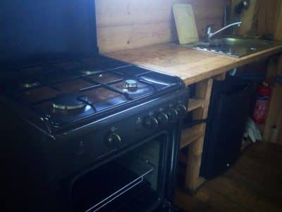 Cuisine rustique dans un chalet en bois, avec un four à gaz et un évier en inox.
