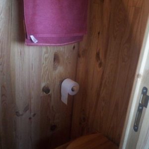 Toilettes en bois dans un hébergement insolite, ambiance chaleureuse et naturelle.