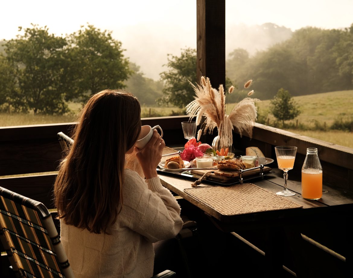 Terrasse en bois avec vue sur la nature, petit-déjeuner gourmand et ambiance paisible.