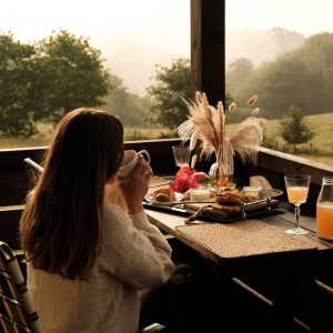 Terrasse en bois avec vue sur la nature, petit-déjeuner gourmand et ambiance paisible.