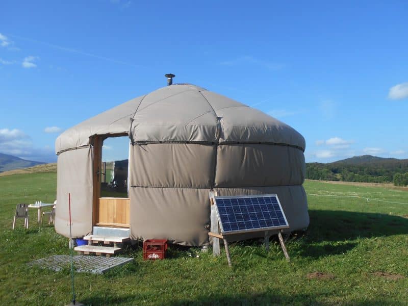 Yourte confortable en pleine nature, avec panneaux solaires et vue sur les collines.