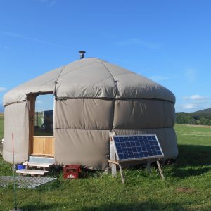 Yourte spacieuse en pleine nature, avec panneaux solaires et vue sur les collines verdoyantes.