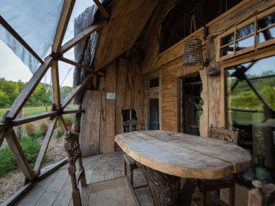 Cabane en bois avec une grande table rustique et des fenêtres panoramiques sur la nature.