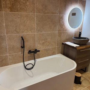 Salle de bain moderne avec baignoire élégante et miroir lumineux, ambiance chaleureuse.