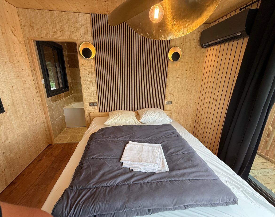 Chalet moderne en bois, avec lit douillet et décoration épurée, ambiance chaleureuse.